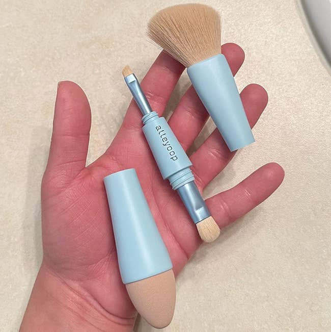 reviewer with sponge brush head, blush brush head, eyeliner brush, and eyeshadow brush in hand