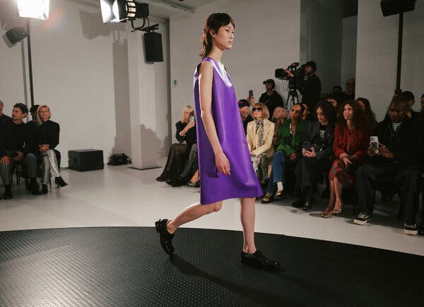 A model walks the runway in a grape-color sleeveless shift.