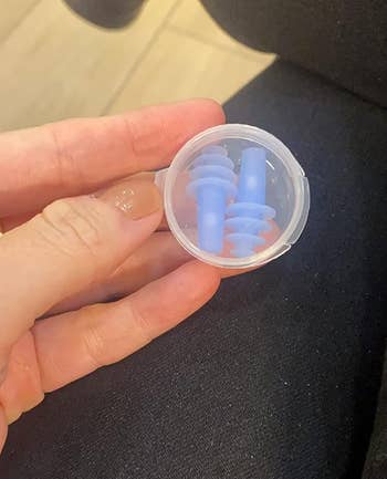 A reviewer holding the clear container with a pair of earplanes inside
