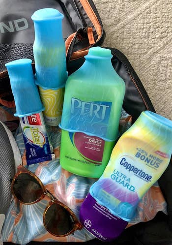 Bottles of sunscreen, toothpaste, and conditioner with the leak-proofing sleeves on them