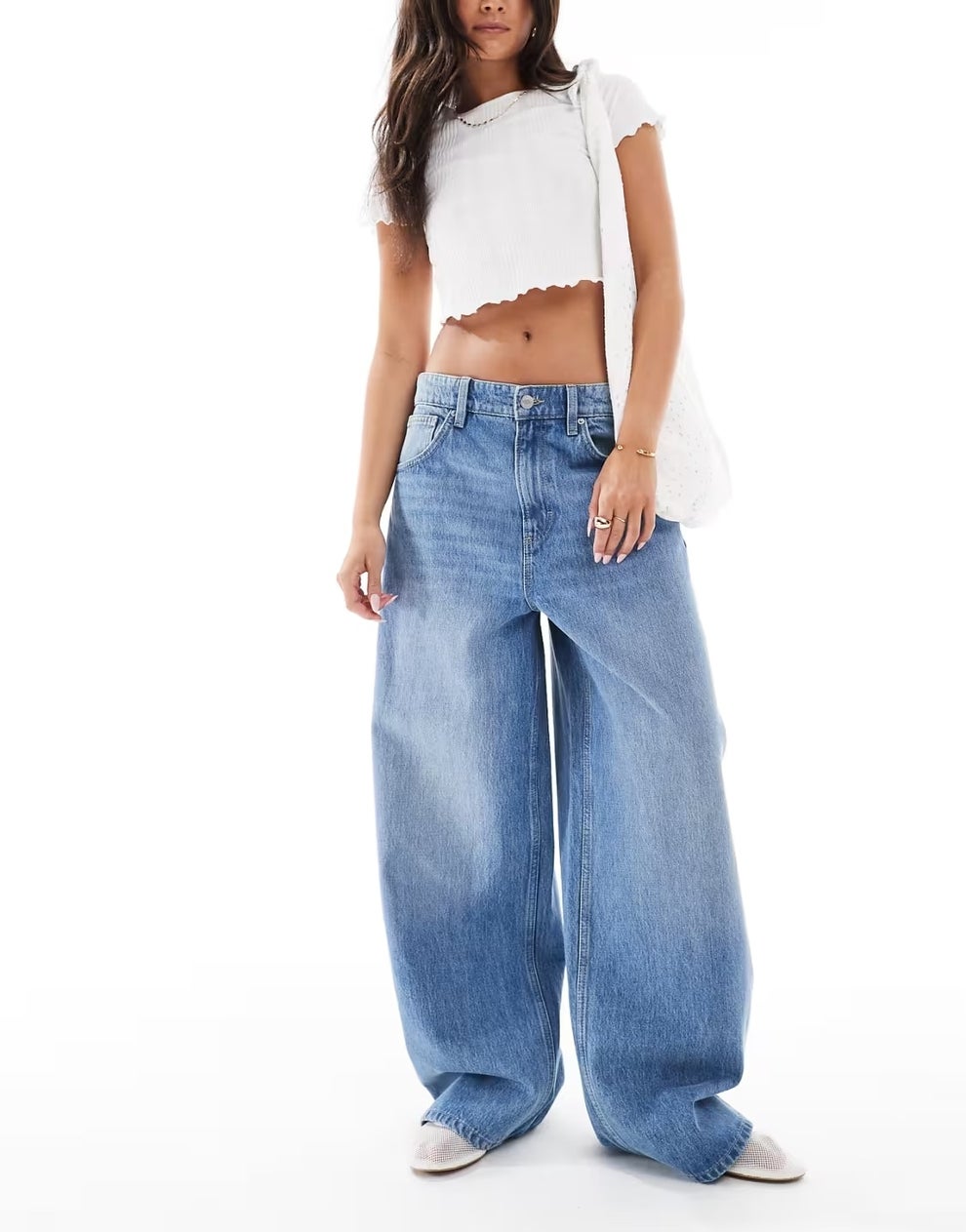 Person wearing a white cropped top, wide-leg jeans, and white sneakers