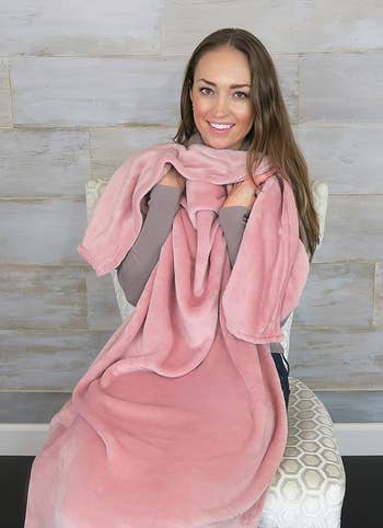 model holding up the pink travel blanket
