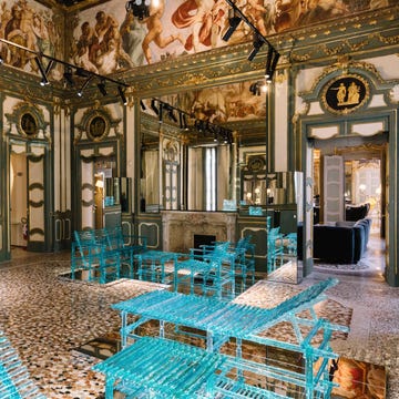 A modern seating area with transparent turquoise furniture in an ornate room.