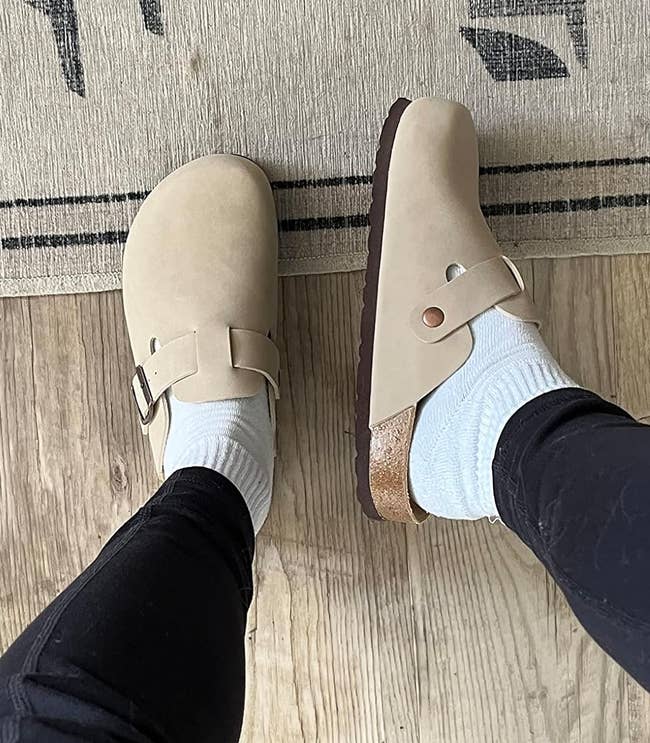 a reviewer showing the top and side view of the beige clogs