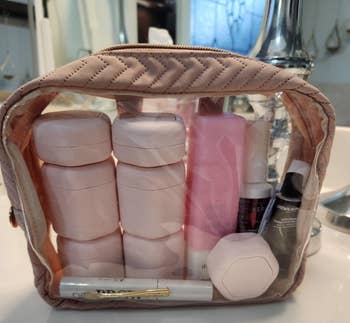 Clear travel toiletry bag with some of the pink capsules inside