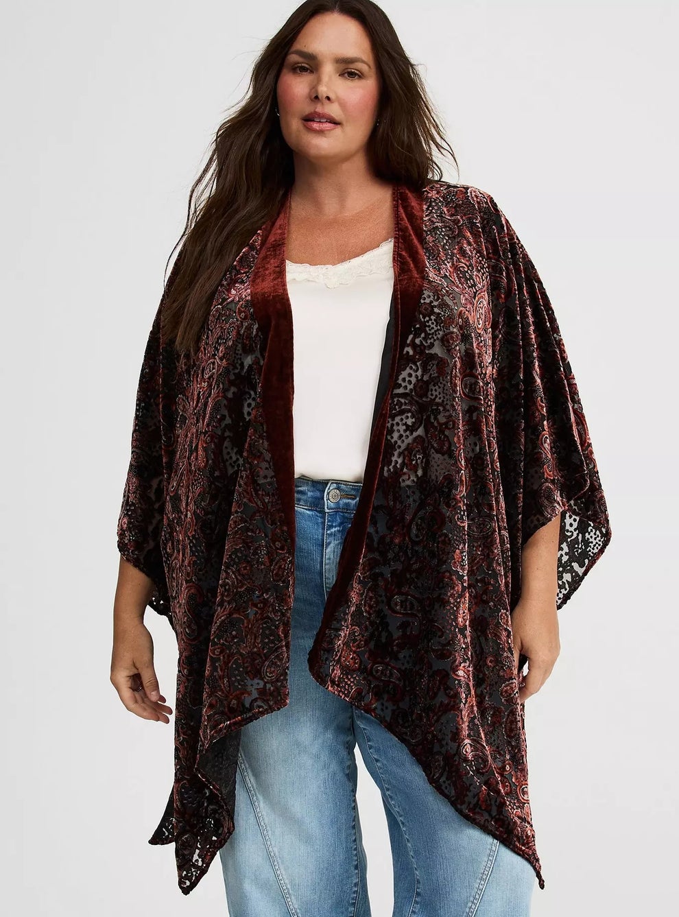 Person wearing a flowy patterned shawl over a white top and jeans