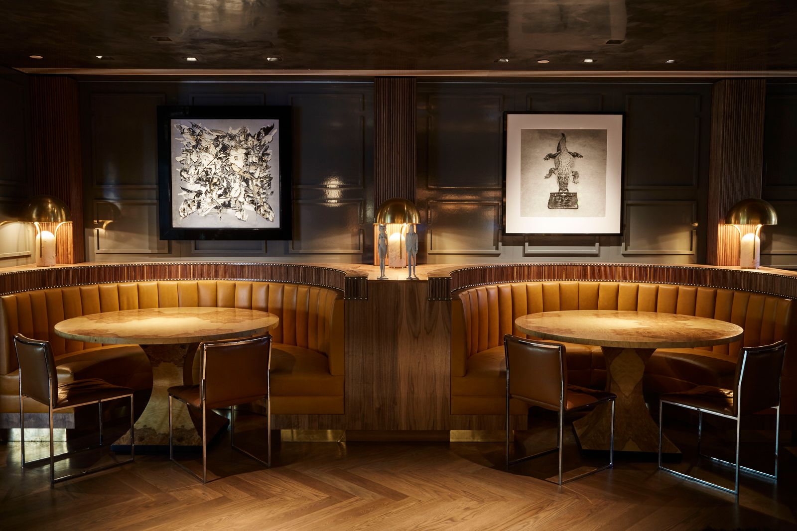 An elegant bar interior with booth seating and framed photographs on the wall.
