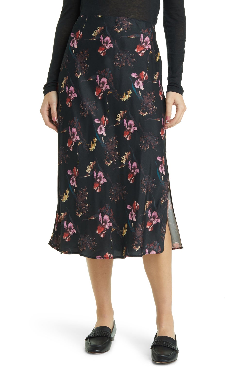 Person wearing a floral-patterned skirt with a black top and black shoes. Skirt has side slit detail