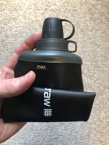 Hand holding a collapsible black water bottle with 