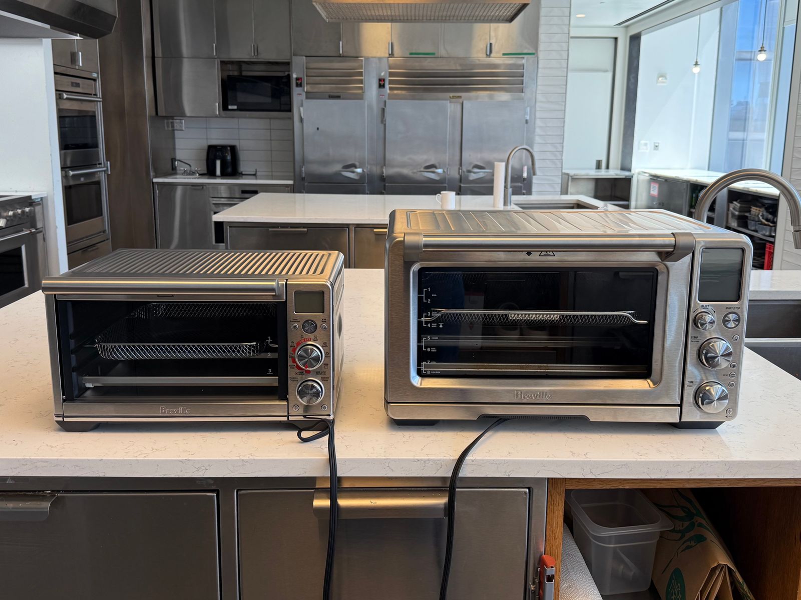 A Breville Smart Oven Air Fryer Compact next to a Breville Smart Oven Air Fryer Pro