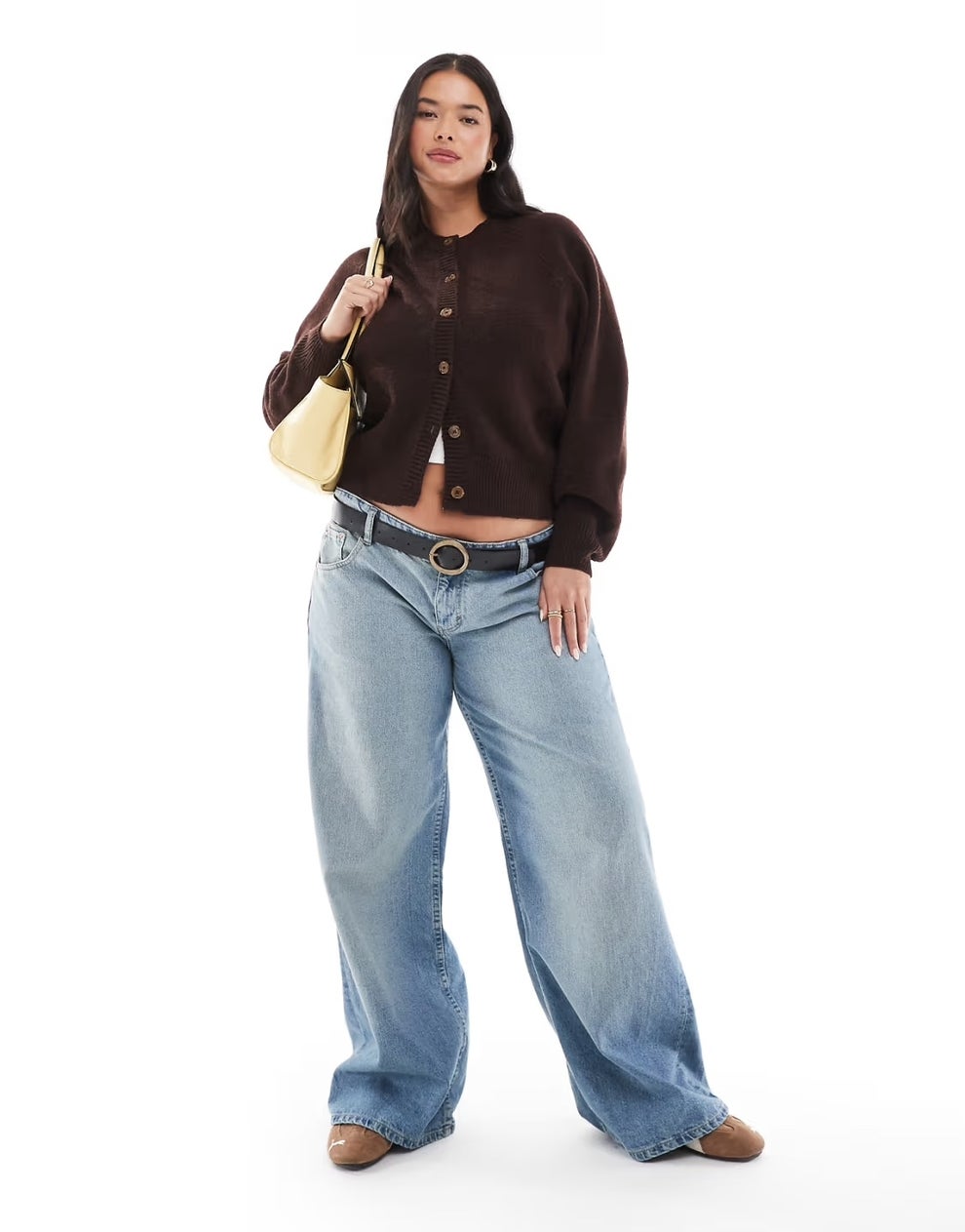 model in wide-leg jeans and cardigan, carrying a shoulder bag