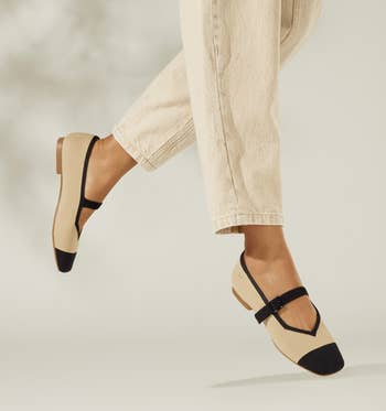 Person wearing beige and black Mary Jane flats with beige pants, showcasing a stylish footwear option