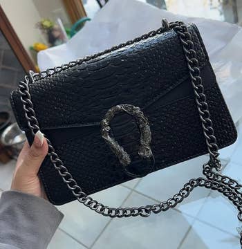 reviewer holding black purse