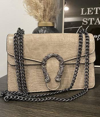 Tan handbag with a silver chain strap and a snakeskin accent