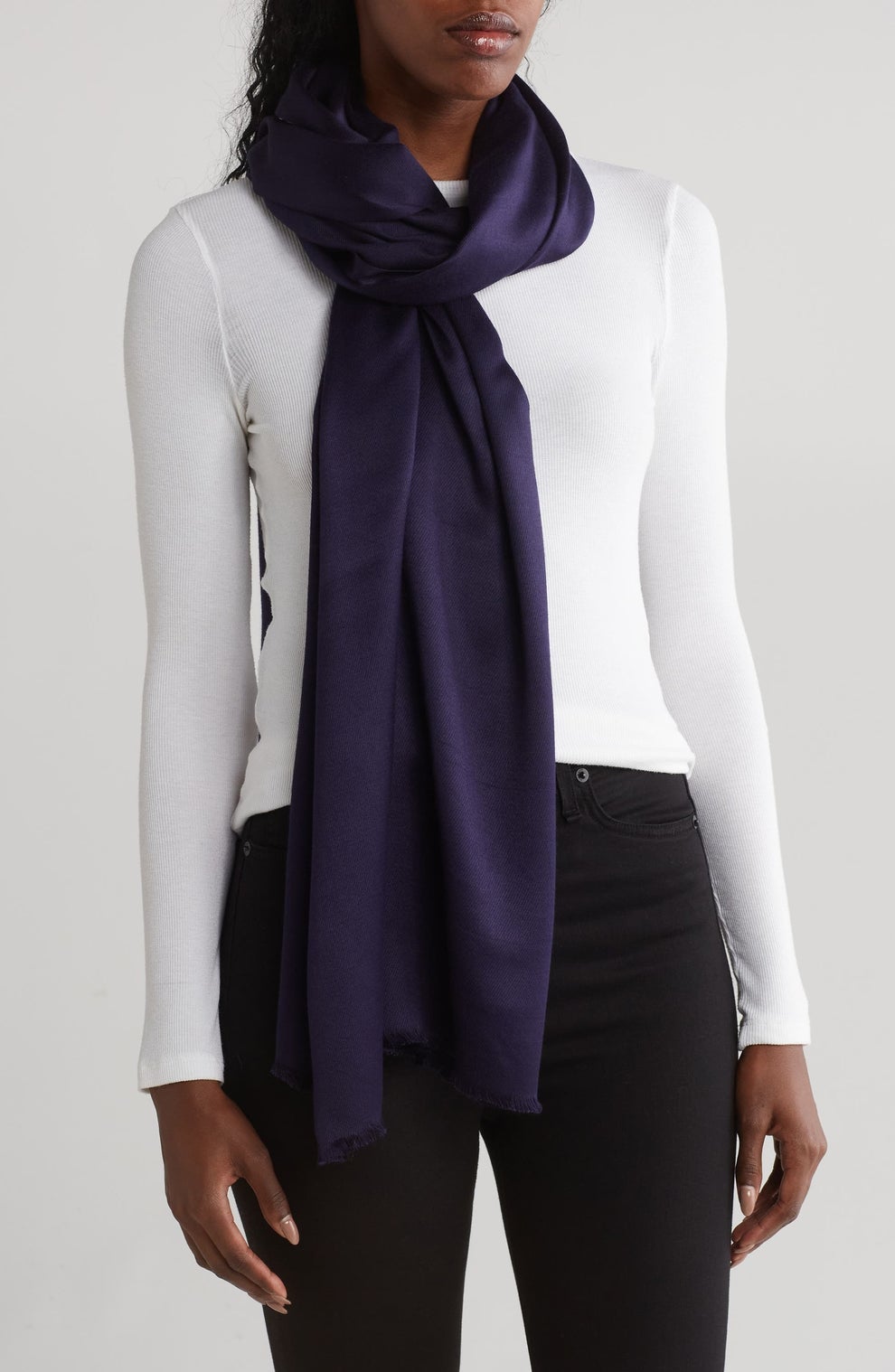 A person wearing a silky scarf in navy over a white top and black pants