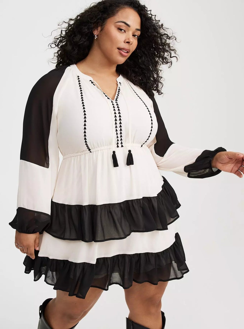 Person modeling a flowing, tiered dress with semi-sheer sleeves and tassel details