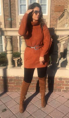 Reviewer posing in a dark orange sweater dress, black leggings, brown knee-high boots, and sunglasses