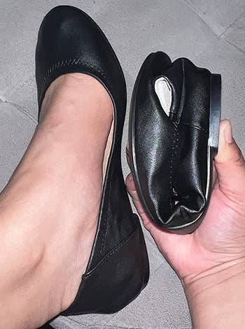 reviewer wearing one of the black flats and holding the other, which is folded in half