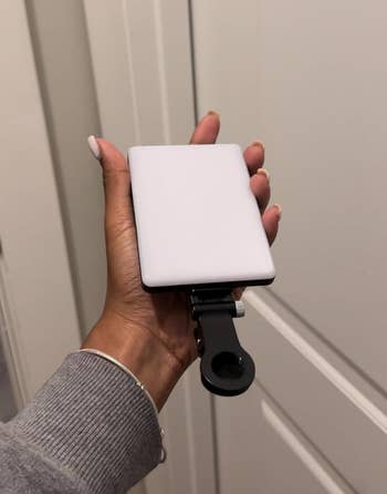 reviewer holding a portable charger with attached phone stand