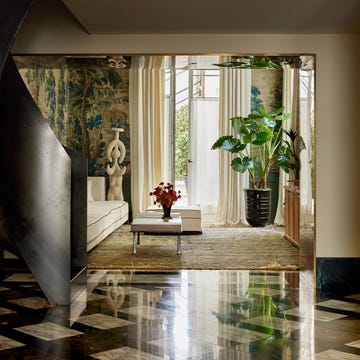 Contemporary interior space featuring a living area with a large window, a potted plant, and a sculpture.