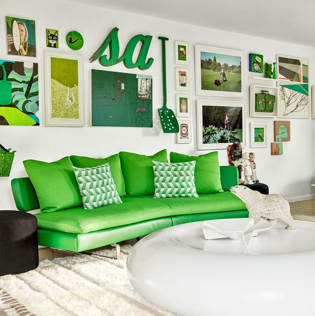 a living room with a curvey neon green sofa and a large round donut shaped white cocktail table and artwork on the wall in white frames and green accented artwork and a dark black round side table