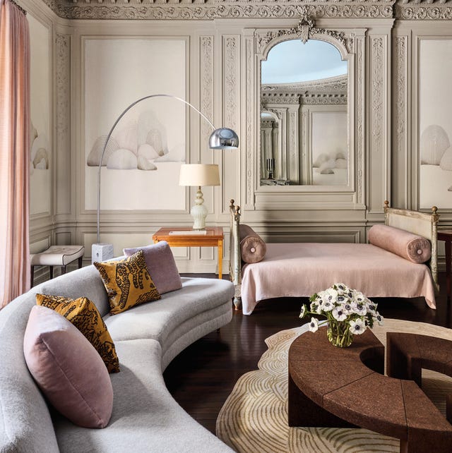 parisian living area with richly molded walls and ceilings and a curvaceous sofa and a daybed at back and a sectional low round coffee table at center