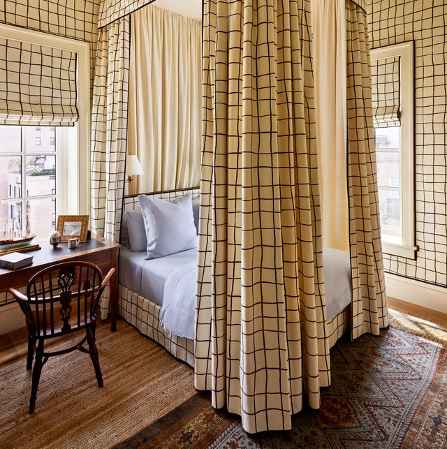 four poster bed with high cream curtains with large blue checks and matching roman shades and bedskirt and wallpaper