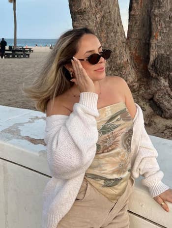 reviewer wearing the oval sunglasses near a beach