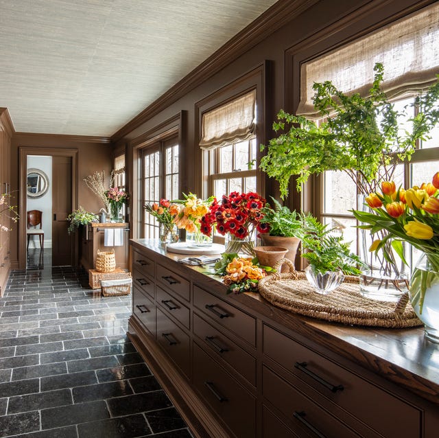 a kitchen with a countertop full of flowers in various containers and a gray tile floor