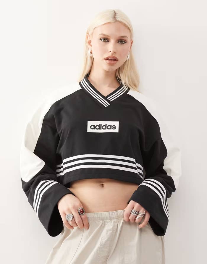 Person in a sporty black and white Adidas crop top with logo, oversized sleeves, and beige pants