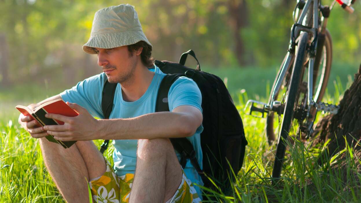 Man reading a book with bicycle in backgroune