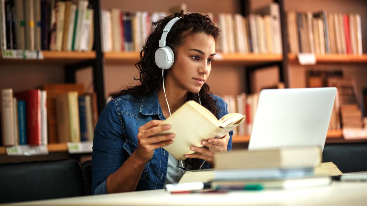Young woman studying with book and laptop