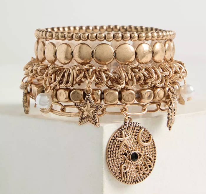Stack of gold-tone bracelets with star and moon charms
