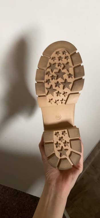 Sole of a boot with a unique star pattern tread held up by a person's hand