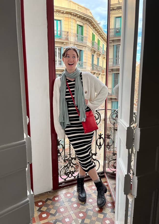 reviewer wearing the light blue scarf with a striped dress and a white cardigan
