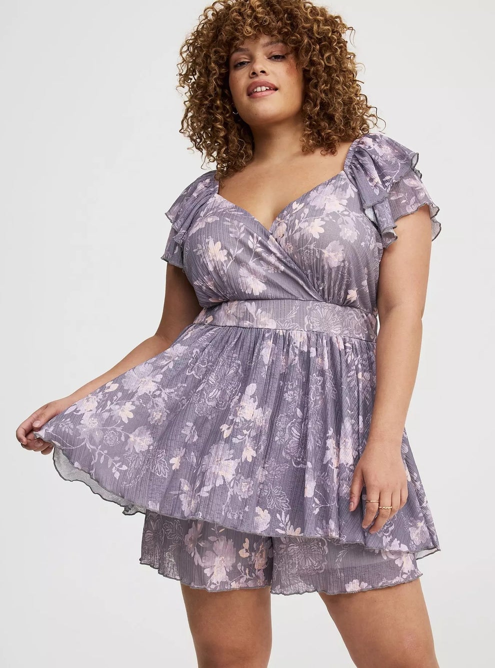 Model modeling a floral, flowy, romper with ruffled sleeves and a V-neckline