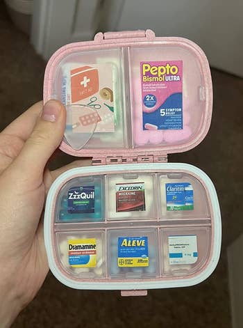 Reviewer holding their pink pill organizer filled with pills and with the compartments labeled 