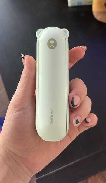 A reviewer holding the green mini fan