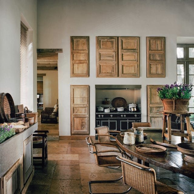 a dining kitchen area with a large table and on the back wall are wooden doors over an expensive black range