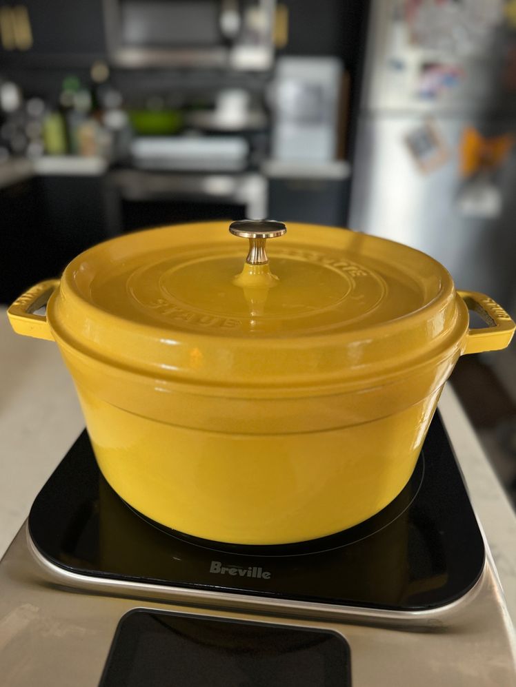 Yellow Staub Cocotte on induction burner with kitchen in the background.