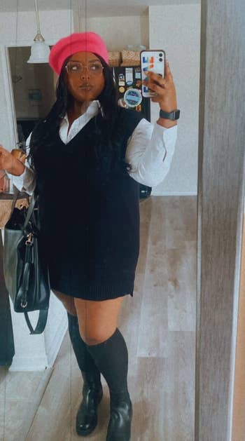 reviewer wearing the black sweater vest over a white collard shirt with a red beret and black shoes and knee high socks