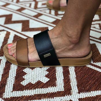 Close-up of a reviewer's feet wearing two-toned sandals