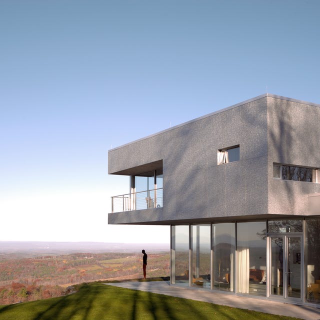 a person standing outside a modern concrete building on a hill