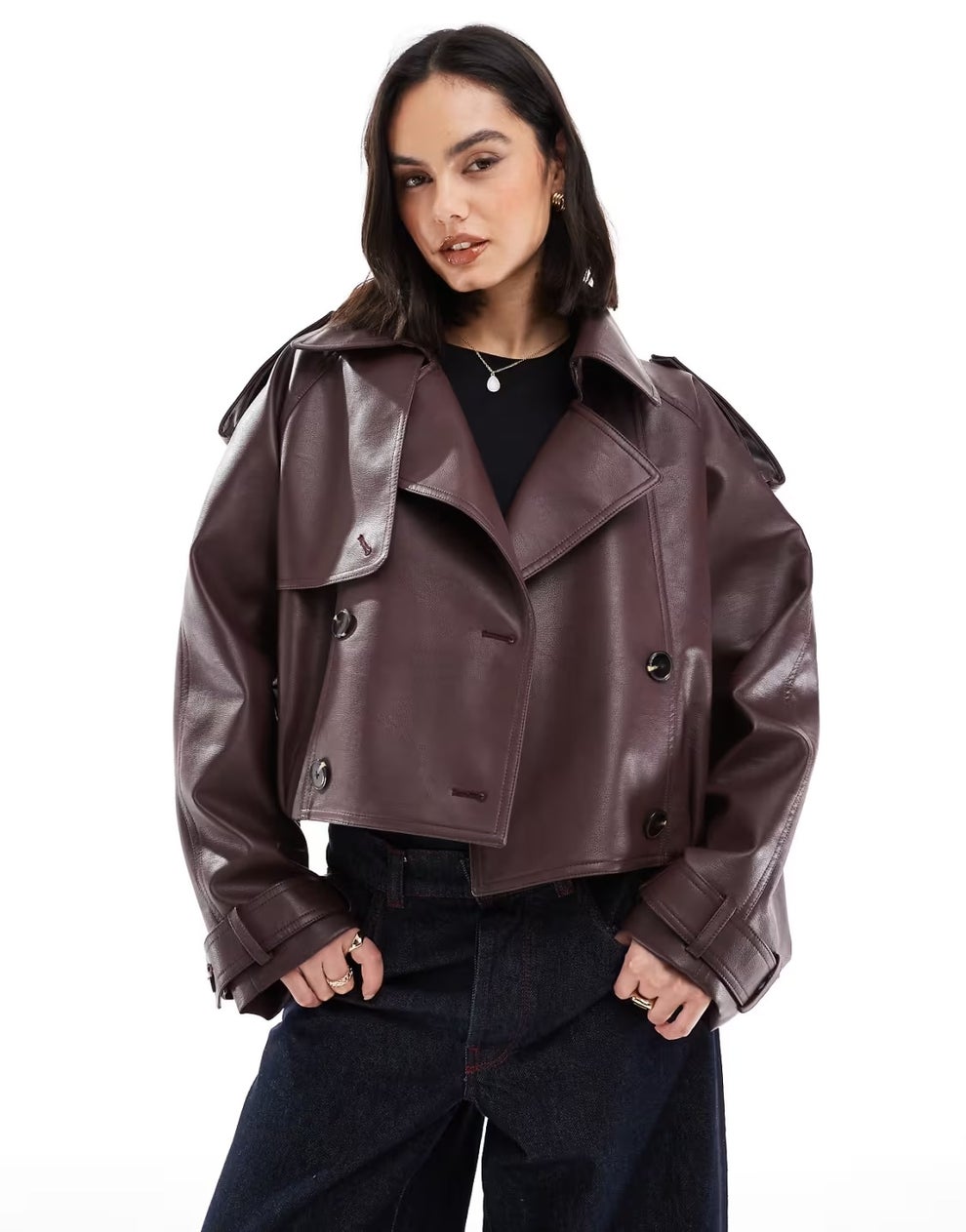 Person wearing a cropped faux leather jacket and jeans, posing confidently