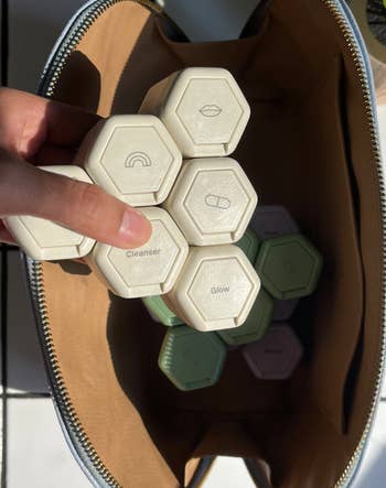 hand pulls out same capsules all stacked together in a white color from cosmetics bag